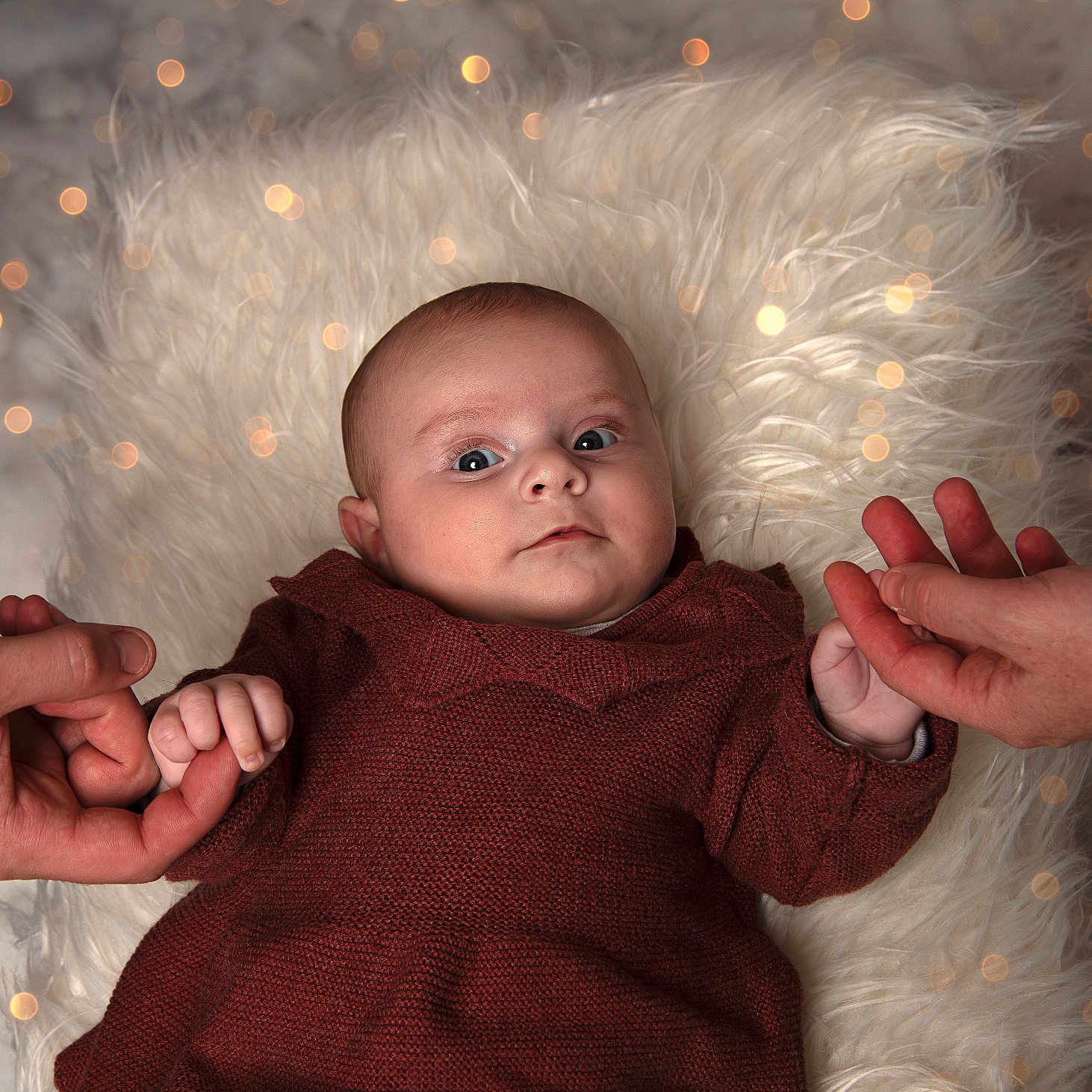 Maddie participe au concours pour gagner de l'argent avec cette photo : baby, bokeh, child, close_up, cozy, cute, expression, face, fluffy_rug, hands, holding_hands, human, indoor, infant, knitwear, portrait, skin, soft_lighting, texture, warm_colors