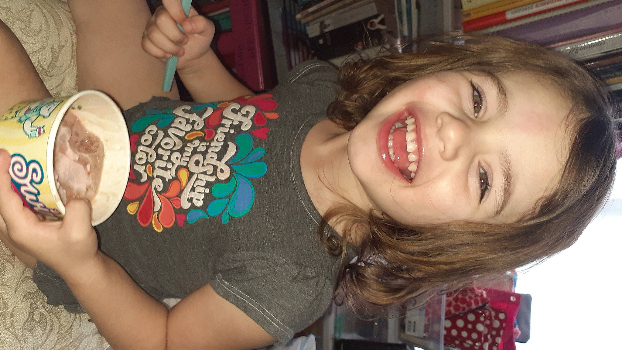 Briella is registered to the contest to win money with this photo: arm, black_hair, brown_hair, child, clothing, eyelash, finger, food, fun, happy, iris, joy, mouth, nail, nose, party, person, skin, smile, t_shirt