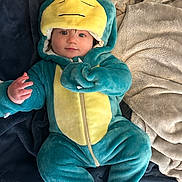 Kode joined the competition — help win amazing prizes! baby, blanket, blue, child, clothing, costume, cozy, cute, dinosaur, face, indoor, infant, lying_down, onesie, person, portrait, smiling, soft, warm, yellow