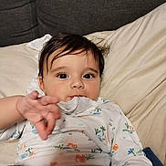 Youcef a rejoint le concours — aidez-le/la à gagner de superbes lots ! baby, child, infant, couch, clothing, onesie, hand, face, eyes, hair, indoors, pillow, blanket, sitting, cute, expression, person, young, portrait, reaching
