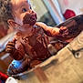 Kaïssy a rejoint le concours — aidez-le/la à gagner de superbes lots ! baby, chocolate, messy, smiling, metal_bowl, curly_hair, indoor, child, playful, cute, face, hands, skin, tongue_out, sitting, food, happy, fun, closeup, infant