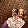 Leah is registered to the contest to win money with this photo: child, girl, posing, sweater, patterned_clothing, purple_pants, wooden_background, outdoor, confident, cute, portrait, fashion, casual, young, person, smirk, long_hair, pigtails, cozy, warm_clothing