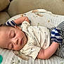 baby, sleeping, infant, mittens, pacifier, cushion, striped_clothing, patterned_shirt, peaceful, resting, closeup, soft_texture, indoors, child, cute, adorable, nap, face, person, comfortable