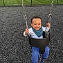 Azarius is registered to the contest to win money with this photo: toddler, child, swing, playground, smiling, happy, outdoor, grass, fence, chain, blue_pants, striped_socks, white_shirt, teal_bib, play, fun, daylight, house, yard, joy