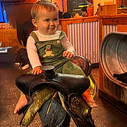Zachary joined the competition — help win amazing prizes! baby, barefoot, child, clothing, decor, face, furniture, indoor, lighting, overalls, people, person, playful, restaurant, rustic, saddle, smile, table, wood, wooden_stand
