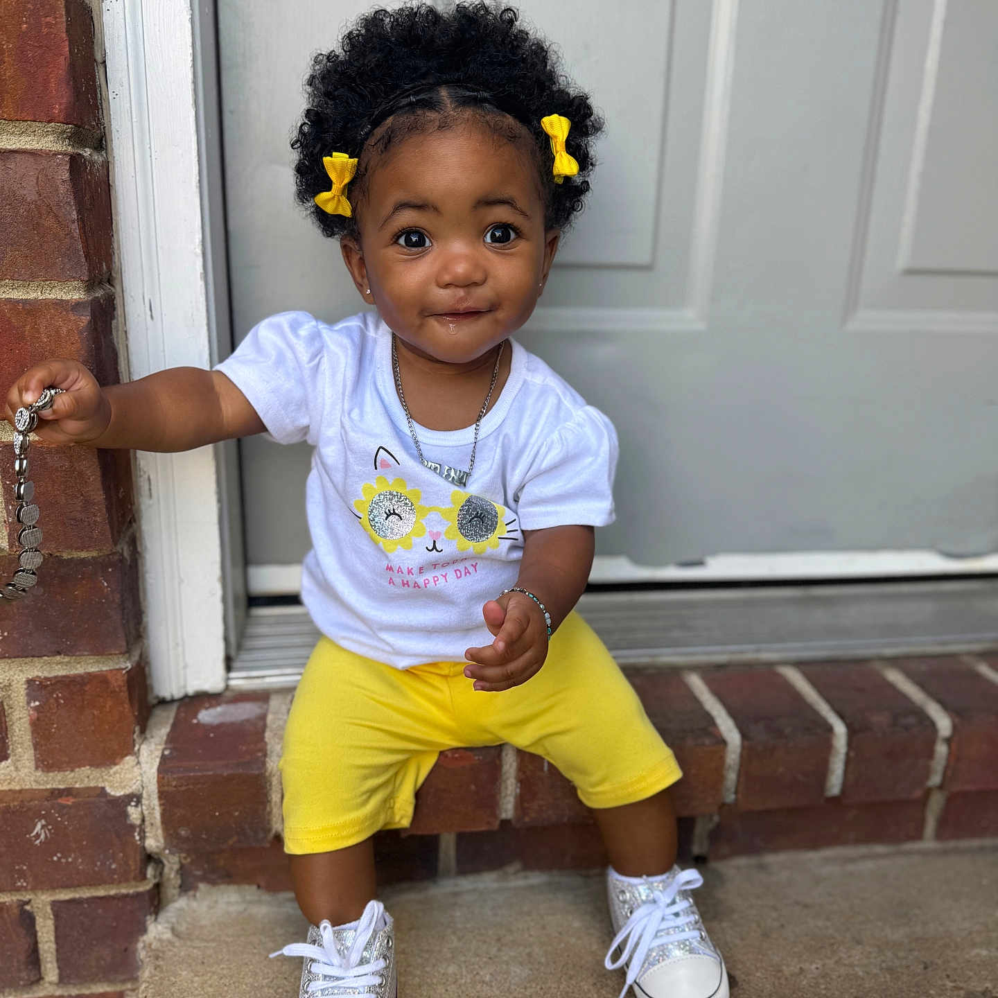 Jalena joined the competition — help win amazing prizes! toddler, child, curly_hair, yellow_bows, white_tshirt, yellow_shorts, sneakers, brick, doorstep, chain, smile, outdoor, portrait, cute, sitting, accessory, happy, person, casual_clothing, daylight