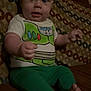 baby, child, indoor, couch, patterned_couch, green_pants, buzz_lightyear_shirt, barefoot, sitting, portrait, face, expression, young_child, furniture, person, cute, hands, feet, wide_eyes, casual_clothing
