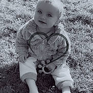 Dorya participe au concours pour gagner de l'argent avec cette photo : baby, black_and_white, child, cute, face, feet, grass, head, infant, jacket, nature, outdoor, pants, playful, portrait, sitting, smile, sock, toy, warm_clothing
