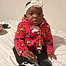 Starr is registered to the contest to win money with this photo: baby, child, indoor, bed, sitting, headband, pacifier, jacket, fuzzy_clothing, colorful, black_pants, sneakers, footwear, cute, portrait, expression, white_background, infant, young_child, warm_clothing