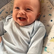 Bobby is registered to the contest to win money with this photo: baby, smiling, infant, child, onesie, cushion, dinosaur_pattern, seat, happy, drool, face, head, cute, indoors, comfort, young, portrait, clothing, baby_girl_or_boy, expression