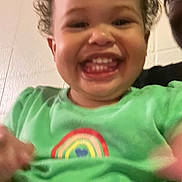 Izabella is registered to the contest to win money with this photo: child, toddler, smiling, happy, green_shirt, rainbow, curly_hair, face, teeth, indoors, person, joy, expression, cute, portrait, closeup, young_child, skin, head, casual