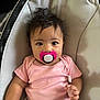 baby, infant, pacifier, pink_onesie, baby_seat, cushion, child, cute, portrait, indoors, person, hair, wide_eyes, comfort, seatbelt, hand, expression, small_child, skin, young