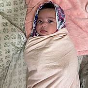 Nevaeh is registered to the contest to win money with this photo: baby, blanket, bed, headscarf, infant, pattern, pink, portrait, wrapped, cozy, cute, child, soft, fabric, face, lying_down, indoors, sleeping_area, comfort, young