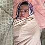 baby, blanket, bed, headscarf, infant, pattern, pink, portrait, wrapped, cozy, cute, child, soft, fabric, face, lying_down, indoors, sleeping_area, comfort, young