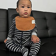 Jacob joined the competition — help win amazing prizes! toddler, child, baby, striped_clothing, bib, black_couch, sitting, indoor, person, footwear, long_sleeve, onesie, young_child, cute, portrait, expression, black_and_white, casual, home, furniture