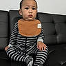 toddler, child, baby, striped_clothing, bib, black_couch, sitting, indoor, person, footwear, long_sleeve, onesie, young_child, cute, portrait, expression, black_and_white, casual, home, furniture
