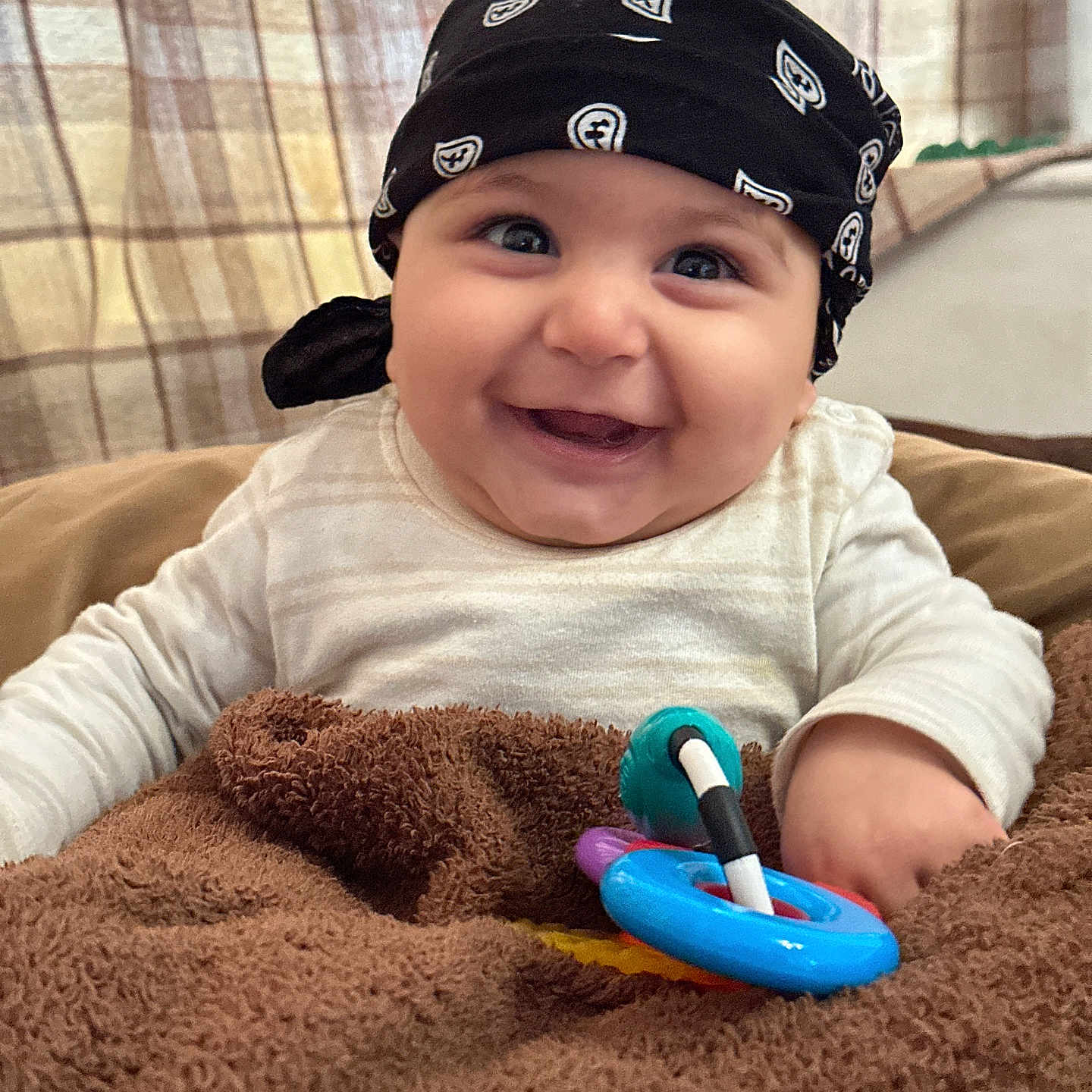 Maaz joined the competition — help win amazing prizes! baby, bandana, blanket, blue, brown, child, clothing, colorful_toy, cute, face, happy, indoor, infant, person, portrait, smile, toy, white_clothing, window, young