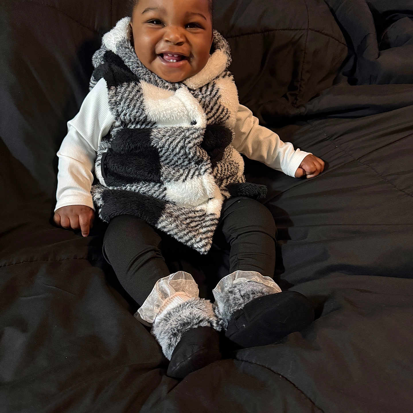 Demechala joined the competition — help win amazing prizes! baby, smiling, child, indoor, cozy, vest, leggings, booties, black_and_white, couch, happy, cute, portrait, seated, furniture, infant, warm_clothing, fuzzy, home, adorable