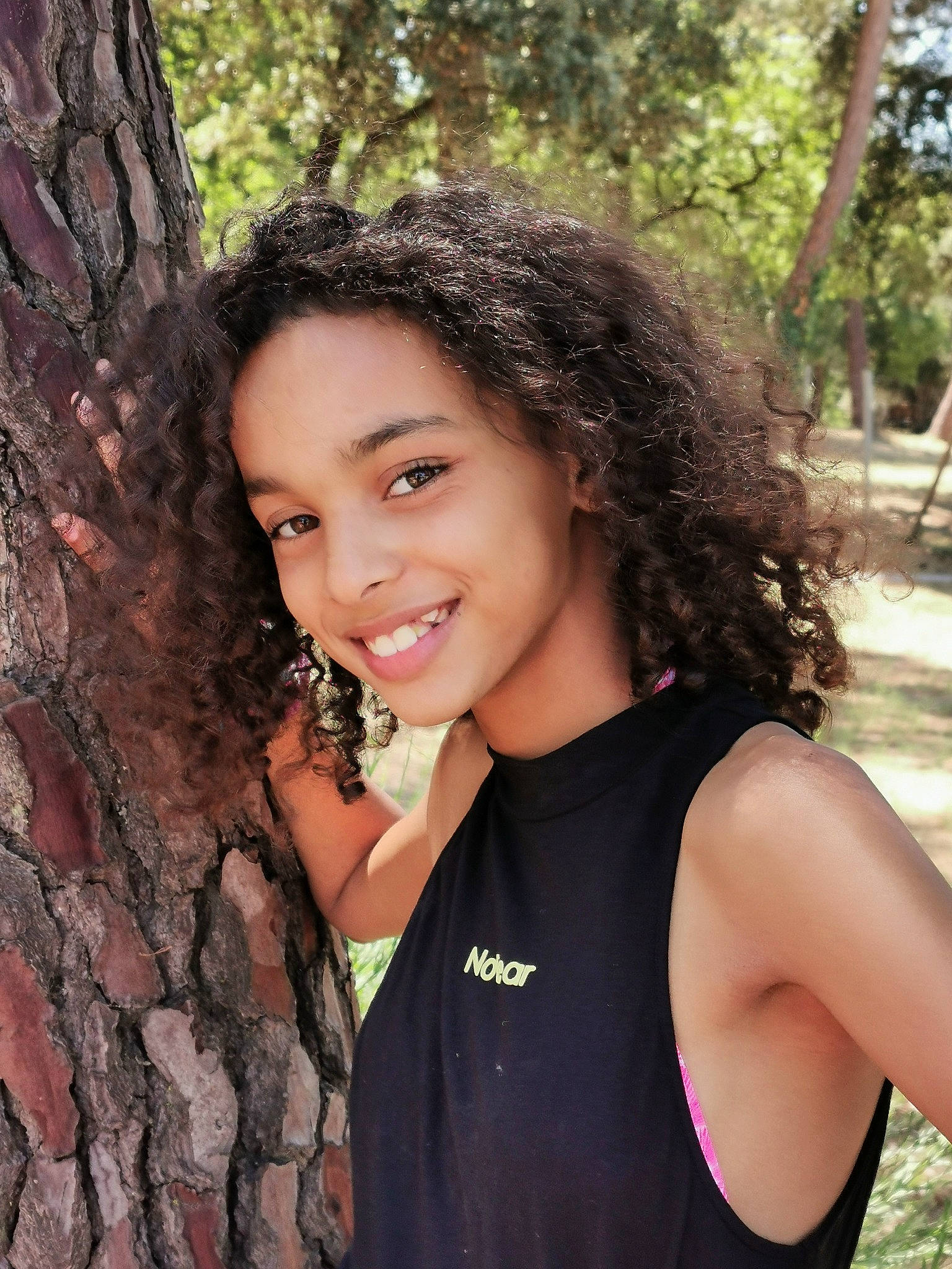 Neïla a rejoint le concours — aidez-le/la à gagner de superbes lots ! beauty, black_hair, eye, facial_expression, flash_photography, forest, grass, happy, joy, leisure, lip, long_hair, people_in_nature, person, skin, sleeveless_shirt, smile, summer, tree, trunk