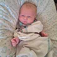 Oaklei Storm is registered to the contest to win money with this photo: baby, infant, blanket, cushion, bed, face, person, newborn, sleepwear, cute, indoors, child, expression, portrait, soft_fabric, pattern, resting, small_hands, lying_down, cozy