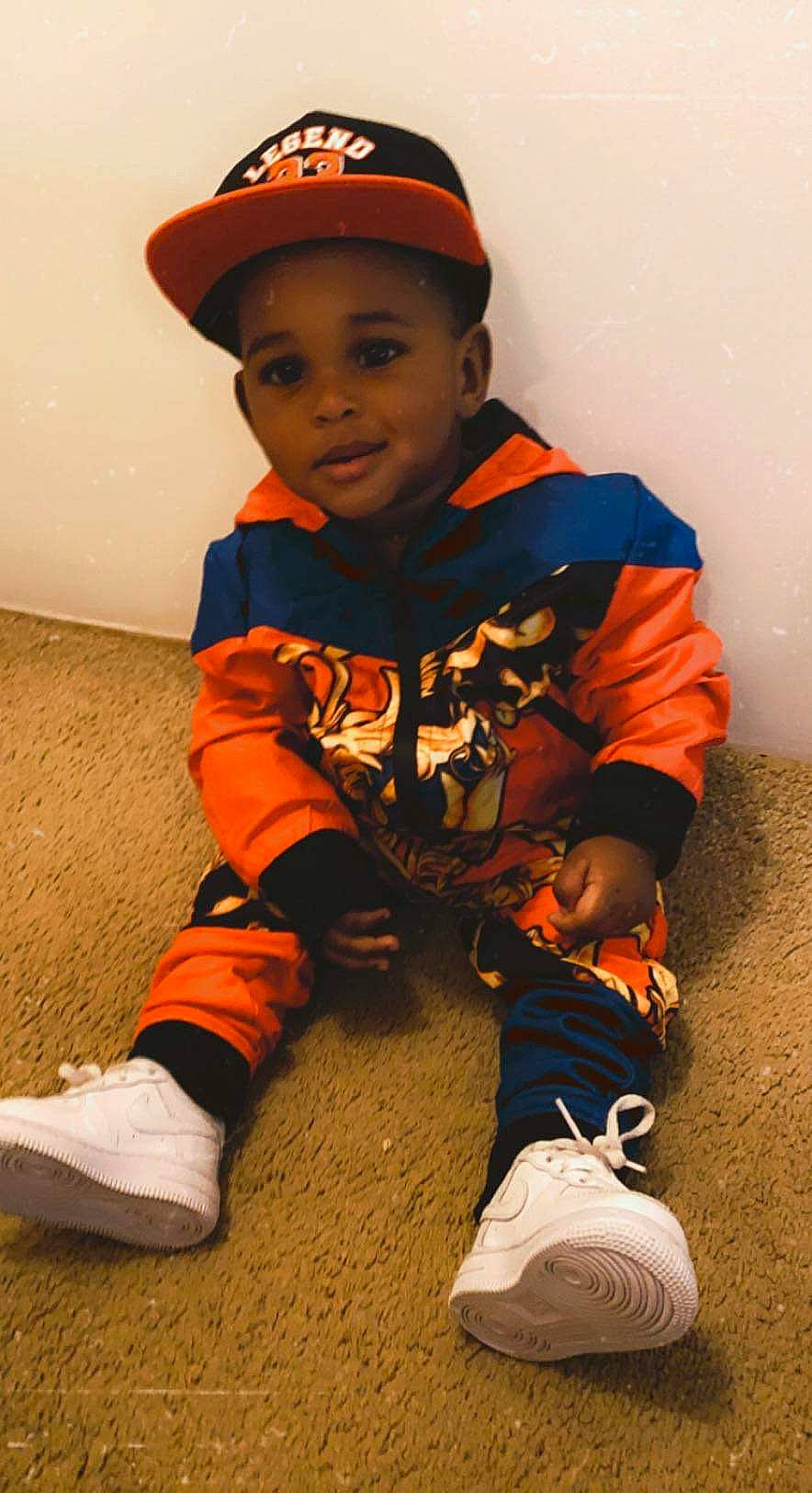 Jamarion joined the competition — help win amazing prizes! baby_toddler_clothing, baseball_cap, cap, child, face, flooring, happy, hat, orange, outdoor_shoe, person, personal_protective_equipment, shoe, sleeve, sneakers, standing, t_shirt, toddler, walking_shoe, white