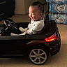 Brayan joined the competition — help win amazing prizes! toddler, child, toy_car, indoor, smiling, happy, playtime, floor, bottled_water, stack, vehicle, miniature, black, person, joyful, laughing, head, clothing, wheels, seat