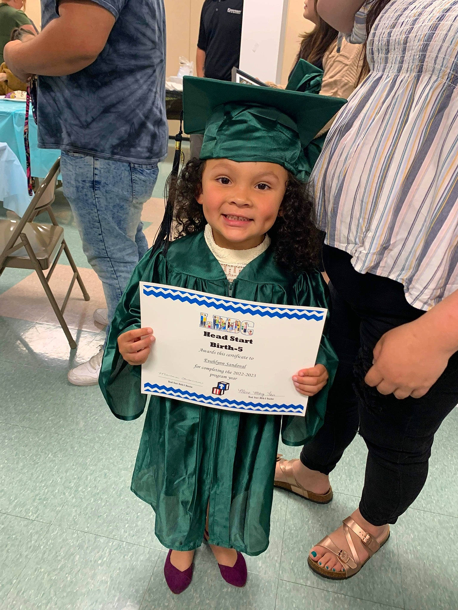 Evahlynn joined the competition — help win amazing prizes! academic_dress, academic_institution, chair, child, clothing, event, fun, gesture, graduation, happy, hat, headgear, headwear, joy, mortarboard, person, public_event, sandal, scholar, smile