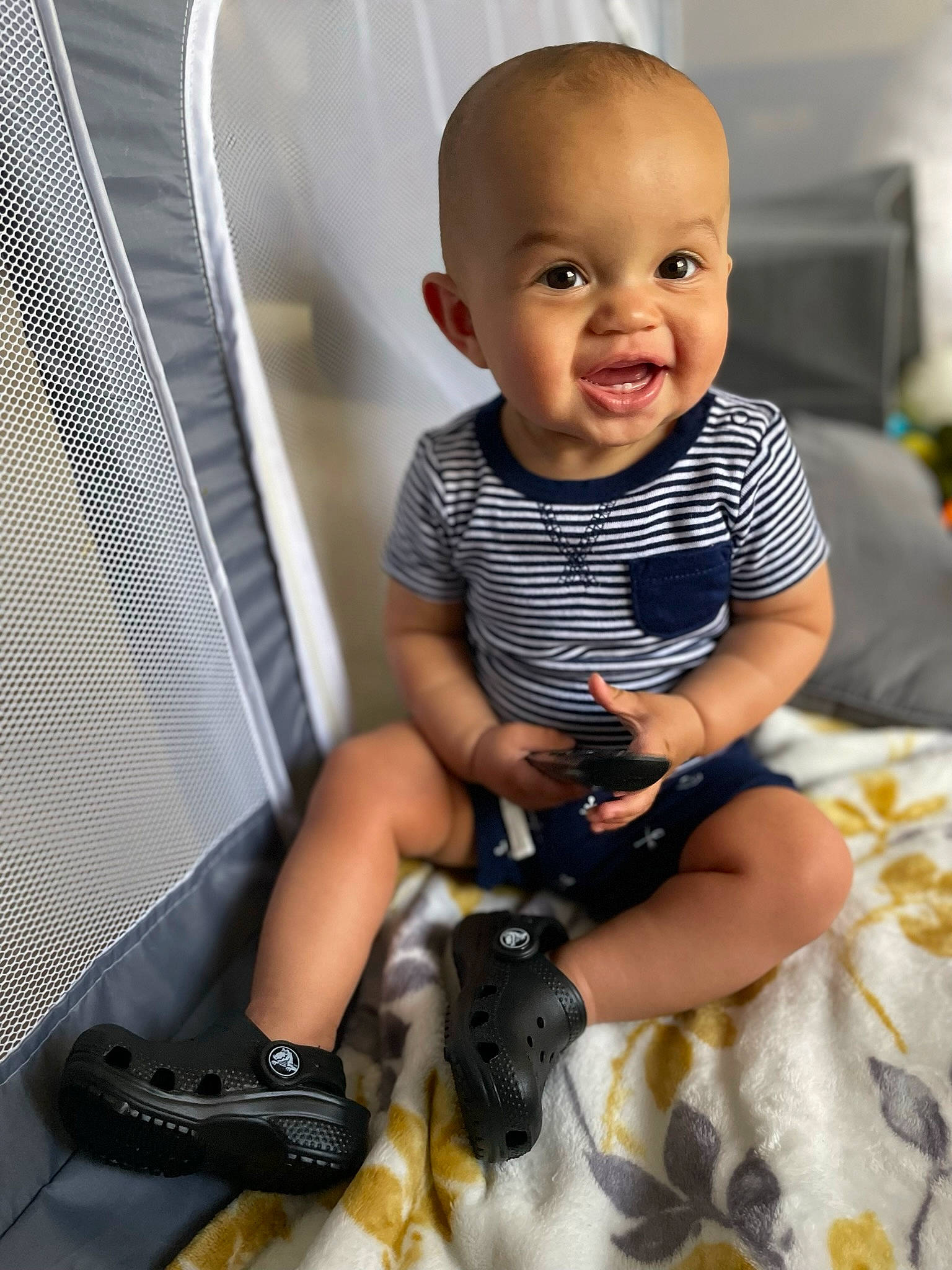 Onyx is registered to the contest to win money with this photo: baby, baby_toddler_clothing, black, camera, child, comfort, fun, happy, human_leg, knee, person, personal_protective_equipment, sandal, shorts, sitting, sleeve, smile, sock, thigh, thumb