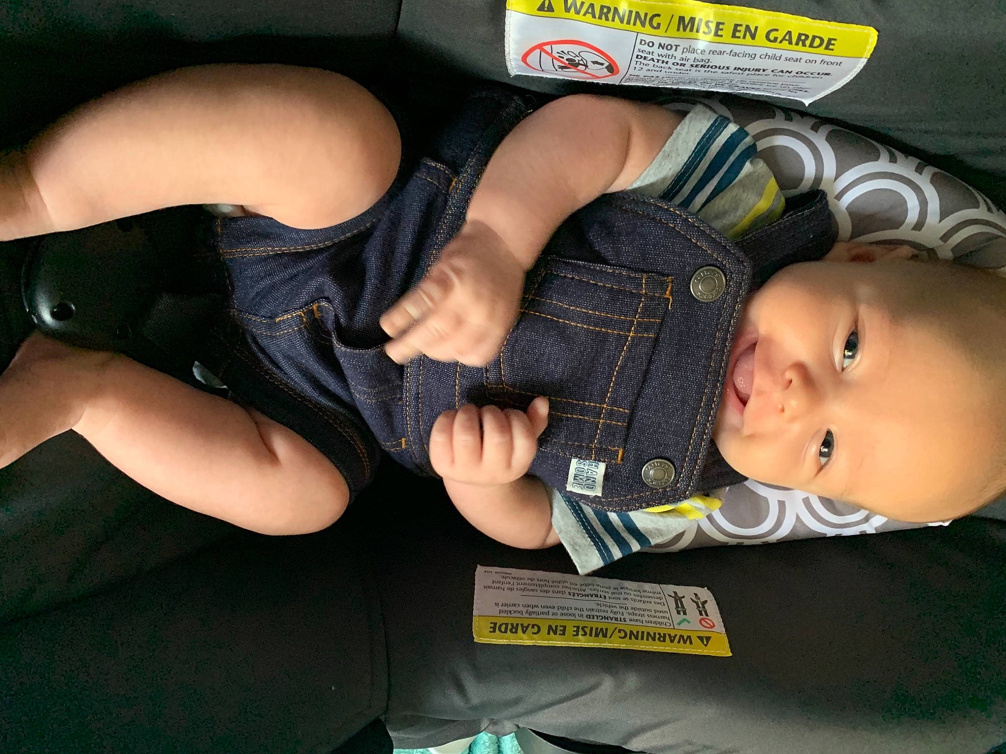 Elliot is registered to the contest to win money with this photo: arm, auto_part, baby, baby_toddler_clothing, car_seat, comfort, finger, gesture, human_body, human_leg, joint, lap, mouth, nail, person, personal_protective_equipment, sitting, thigh, thumb, toddler