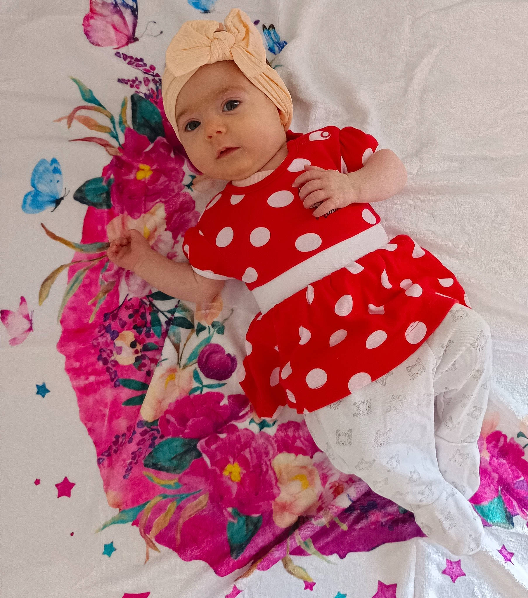 Livia a rejoint le concours — aidez-le/la à gagner de superbes lots ! baby, baby_products, baby_toddler_clothing, bedding, child, dress, fashion_accessory, font, happy, headwear, linens, magenta, pattern, peach, person, petal, pink, sitting, sleeve, t_shirt