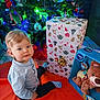Yaël participe au concours pour gagner de l'argent avec cette photo : blue_shirt, box, child, christmas, christmas_tree, decorations, festive, floor, gift, holiday, indoor, ornaments, pine_tree, present, smiling, socks, teddy_bear, toddler, toy, young_child