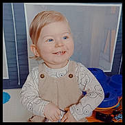 Yaël participe au concours pour gagner de l'argent avec cette photo : baby, blond_hair, blue_eyes, child, hands, happy, indoor, long_sleeve, mesh_panel, nursery, overalls, patterned_shirt, playpen, portrait, sitting, smile, soft_lighting, teeth, toddler, toy