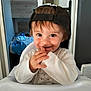toddler, child, smile, high_chair, cap, backwards_cap, indoor, portrait, cute, happy, baby, clothing, face, fingers, brown_eyes, brown_hair, expression, person, seat, room