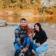 Oliver is registered to the contest to win money with this photo: family, child, man, woman, pregnant, dog, river, outdoor, smiling, casual_clothing, nature, barefoot, bandana, jeans, plaid_shirt, happy, posing, sunlight, sand, trees