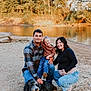 family, child, man, woman, pregnant, dog, river, outdoor, smiling, casual_clothing, nature, barefoot, bandana, jeans, plaid_shirt, happy, posing, sunlight, sand, trees
