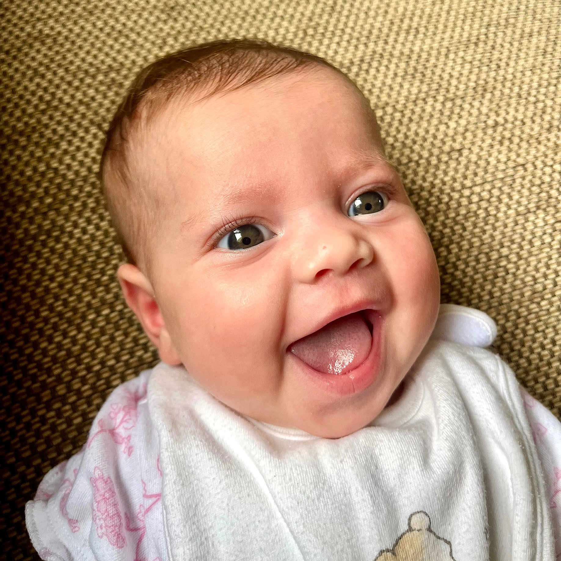 Estelle is registered to the contest to win money with this photo: baby, background, bib, child, close_up, clothing, cute, eyes, face, happy, infant, mouth, person, pink, skin, smiling, teddy_bear, texture, tongue, white