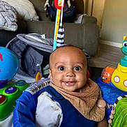 Zion joined the competition — help win amazing prizes! baby, child, smile, face, indoor, toy, activity_center, globe_toy, submarine_toy, bib, clothing, furniture, couch, blanket, floor, person, head, happy, infant, playtime