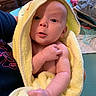 Kemberly joined the competition — help win amazing prizes! baby, newborn, infant, child, portrait, face, eyes, wide_eyed, hooded_towel, yellow_towel, wrapped, held, adult, indoor, bedroom, furniture, blankets, changing_area, skin, close_up