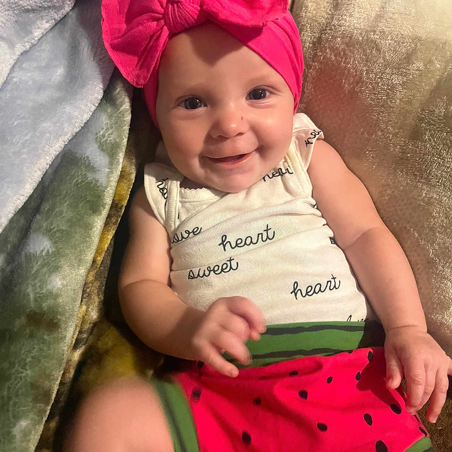 Kemberly joined the competition — help win amazing prizes! baby, infant, child, smiling, portrait, pink_bow, headband, watermelon, outfit, blanket, pillow, bed, indoor, cozy, lying_down, happy, face, arms, hands, photography