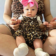 Klara Mae is registered to the contest to win money with this photo: baby, child, infant, portrait, sitting, pink_bow, leopard_print, dress, white_socks, adult, parent, hands, fashion, indoors, close_up, face, eyes, cute, family, photography