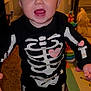 Laney Dru joined the competition — help win amazing prizes! baby, child, indoor, skeleton_costume, headband, pink_bow, smiling, happy, toys, carpet, floor, person, cute, infant, playroom, colorful, expression, standing, barefoot, home