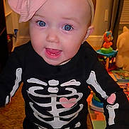 Laney Dru joined the competition — help win amazing prizes! baby, child, skeleton_costume, pink_bow, headband, smiling, blue_eyes, indoor, toy, carpet, hand_holding, cute, toddler, happy, face, person, clothing, earrings, playroom, colorful