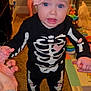 Laney Dru joined the competition — help win amazing prizes! baby, child, skeleton_costume, headband, pink_bow, indoor, carpet, toys, hand_holding, blue_eyes, expression, footwearless, person, cute, infant, playroom, clothing, floor, smile, parent