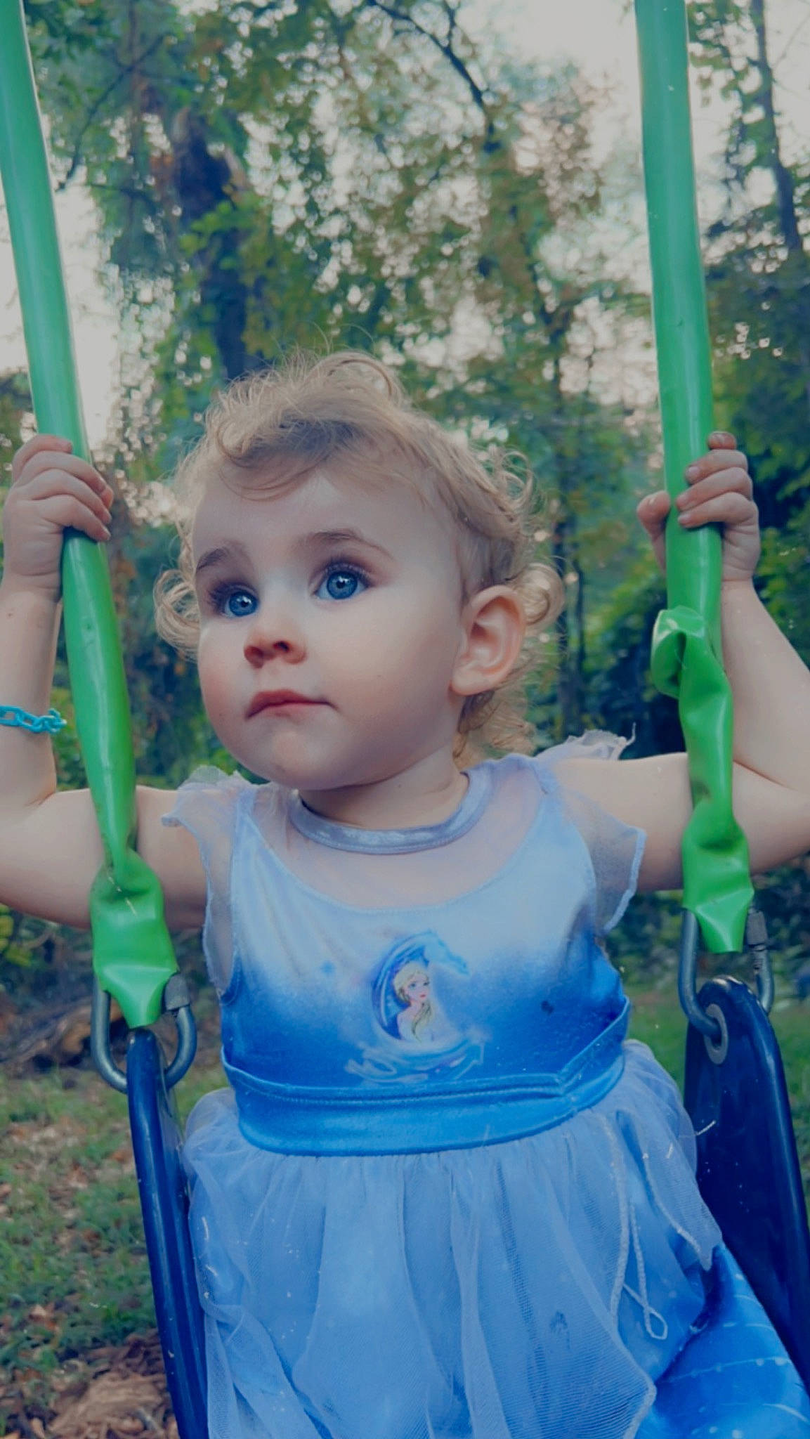 Astrid is registered to the contest to win money with this photo: arm, baby_toddler_clothing, beauty, child, electric_blue, grass, green, hairstyle, happy, leisure, outdoor_play_equipment, people_in_nature, person, pink, plant, recreation, shoulder, skin, swing, toddler