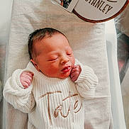 Tate is registered to the contest to win money with this photo: baby, cozy, cushion, cute, embroidered_sign, hospital_bassinet, indoor, infant, instant_photo, knitted_outfit, name_sign, newborn, peaceful, person, portrait, sleeping, small_hands, striped_fabric, tiny_feet, white_clothing