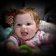 Charlie-Lynn joined the competition — help win amazing prizes! baby, child, smiling, happy, curly_hair, blue_eyes, onesie, reaching, portrait, indoor, closeup, cute, infant, face, person, soft_focus, expression, joyful, baby_toy, blurred_background