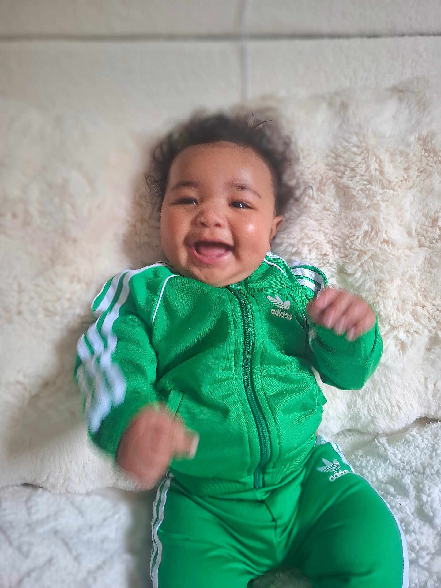 Isaïa participe au concours pour gagner de l'argent avec cette photo : adidas, baby, blanket, child, clothing, cozy, curly_hair, cute, face, green_tracksuit, hands, happy, indoor, infant, lying_down, motion_blur, portrait, smiling, soft_texture, young_child