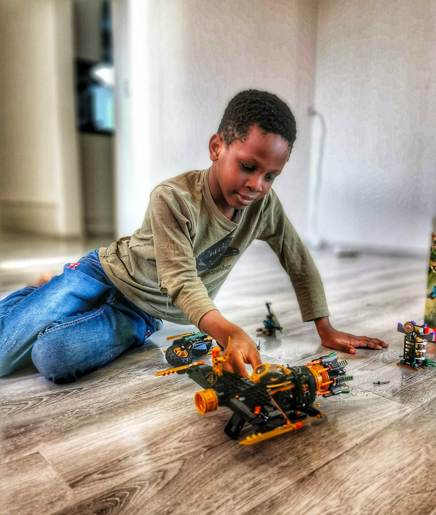 Ryan a rejoint le concours — aidez-le/la à gagner de superbes lots ! automotive_design, automotive_tire, child, engineering, floor, flooring, fun, hardwood, jeans, machine, person, plant, play, recreation, sitting, tire, tool, toy, toy_vehicle, wheel