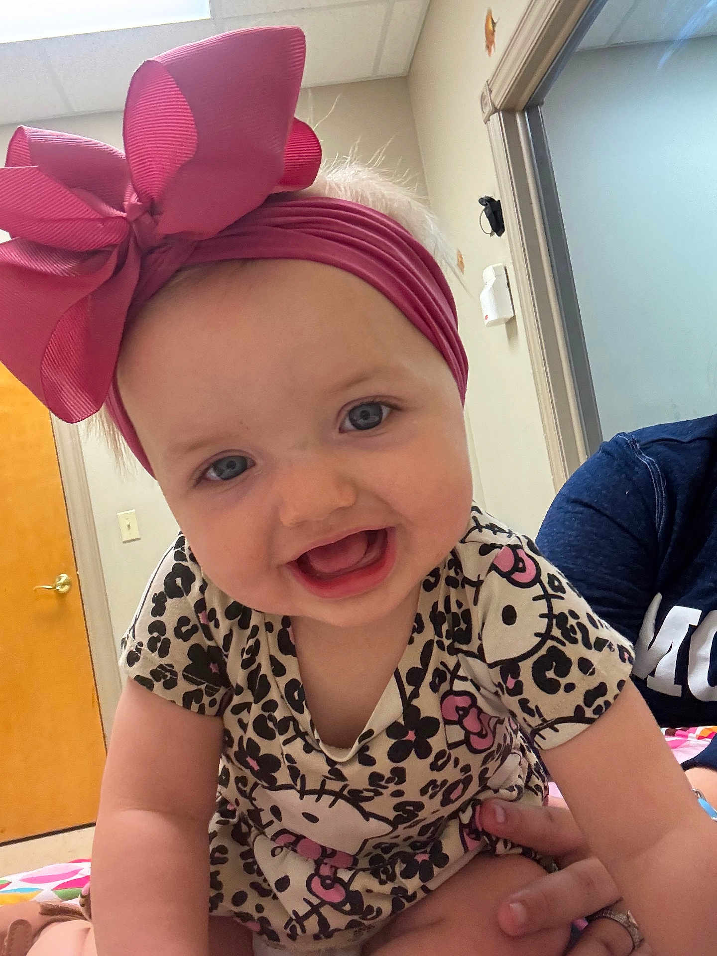 Ashlyn joined the competition — help win amazing prizes! baby, child, headband, pink_bow, hello_kitty, patterned_clothing, smiling, blue_eyes, indoor, hand, person, cute, happy, toddler, short_sleeves, infant, closeup, portrait, skin, human