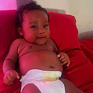 Ahki is registered to the contest to win money with this photo: baby, diaper, infant, cushion, red, drool, cute, skin, chubby, relaxing, indoors, child, smiling, person, portrait, curly_hair, lying_down, plush, comfort, young